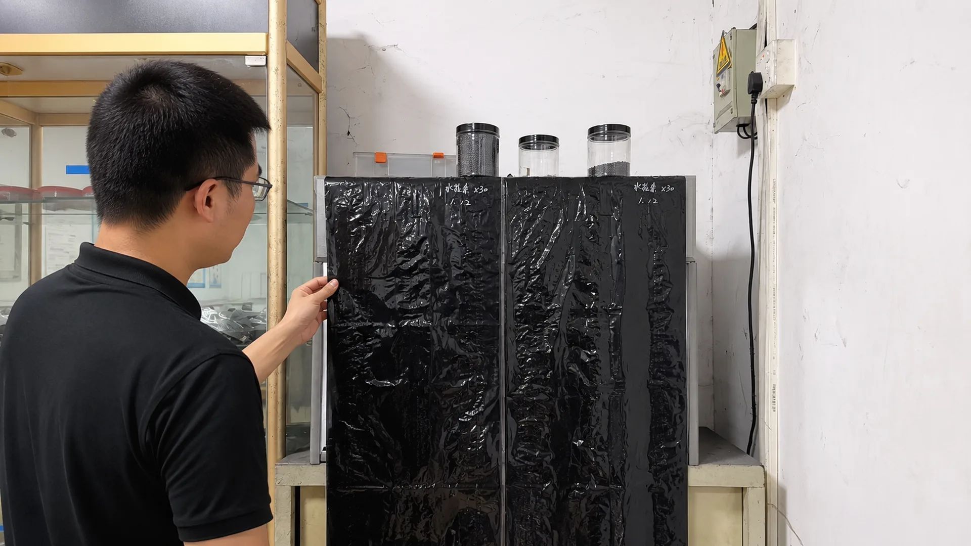 Quality technician inspecting black masterbatch film dispersion at a light box